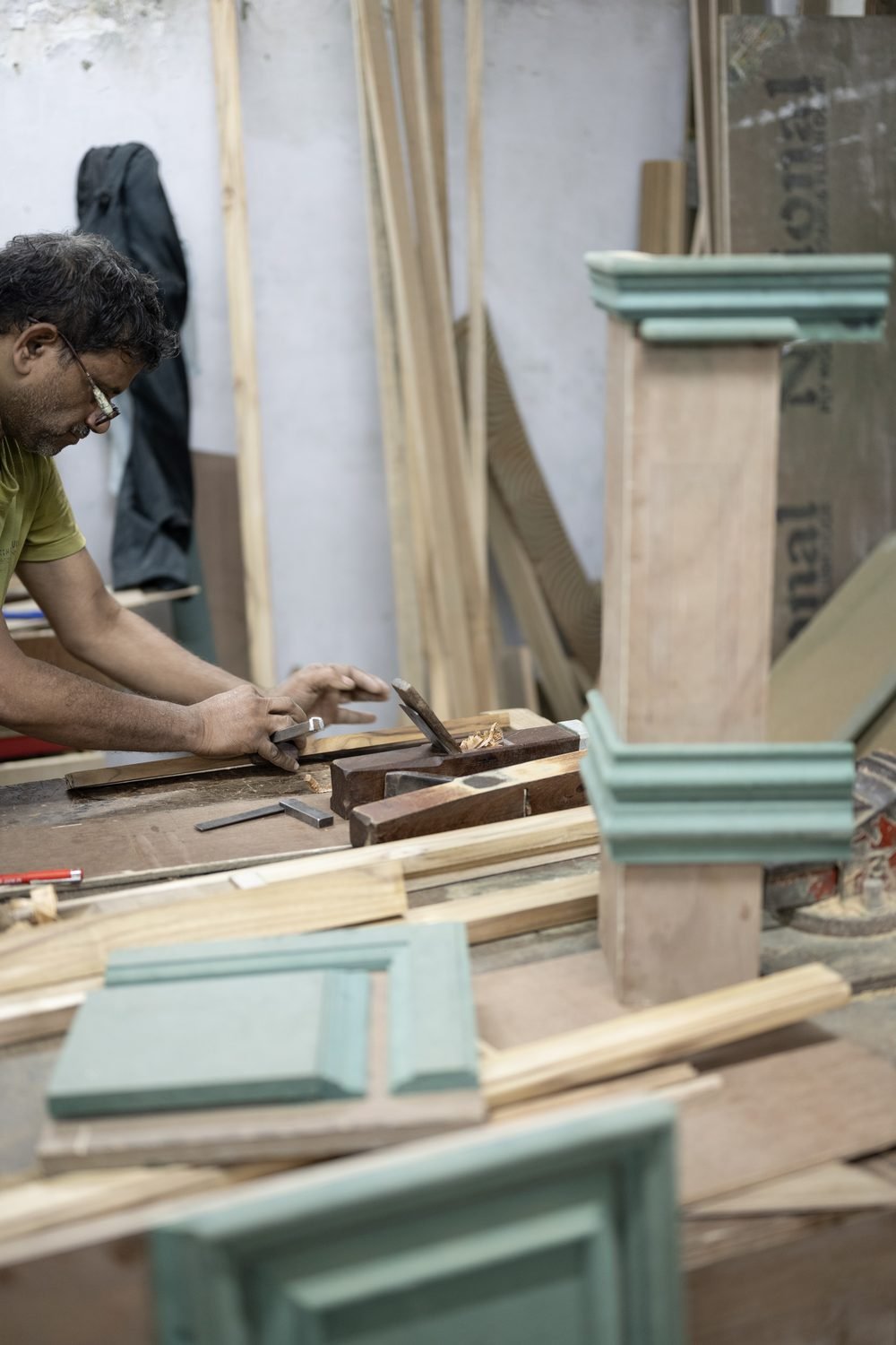 A carpenter planing and fitting timber at the workbench