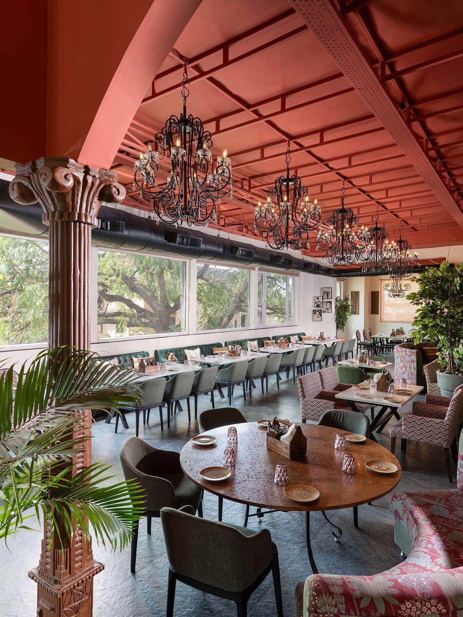 Restaurant interior with a terracotta ceiling, wrought-iron chandeliers and sage banquettes